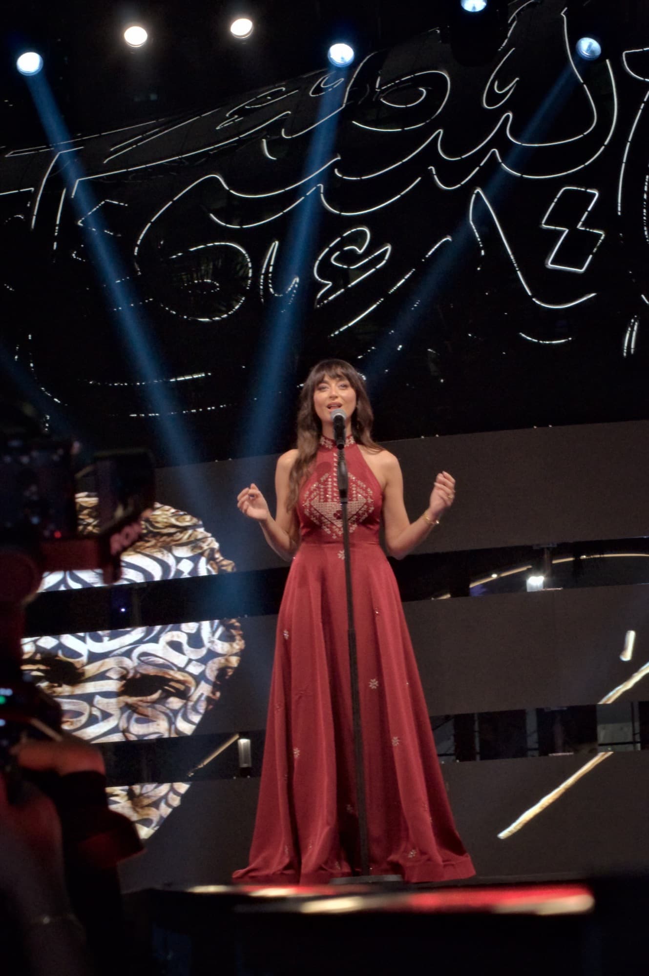 Singer in a red gown performing under stage lights