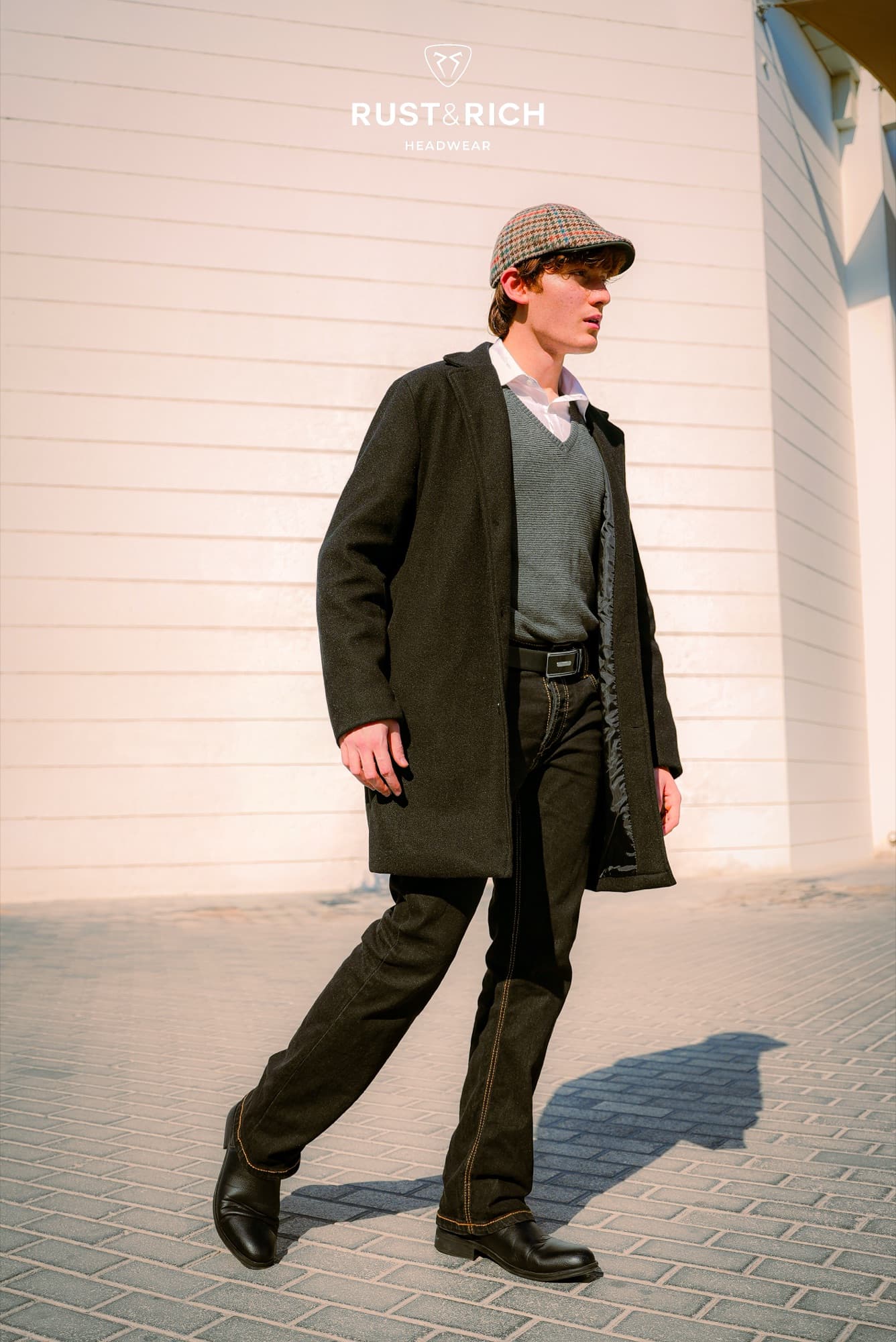 Rust and Rich campaign look in an overcoat and flat cap